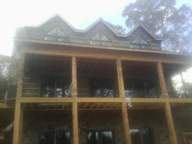 Dormers and porch framing on a large log home under construction — Roof Coating work by our crew in Bernhards Bay