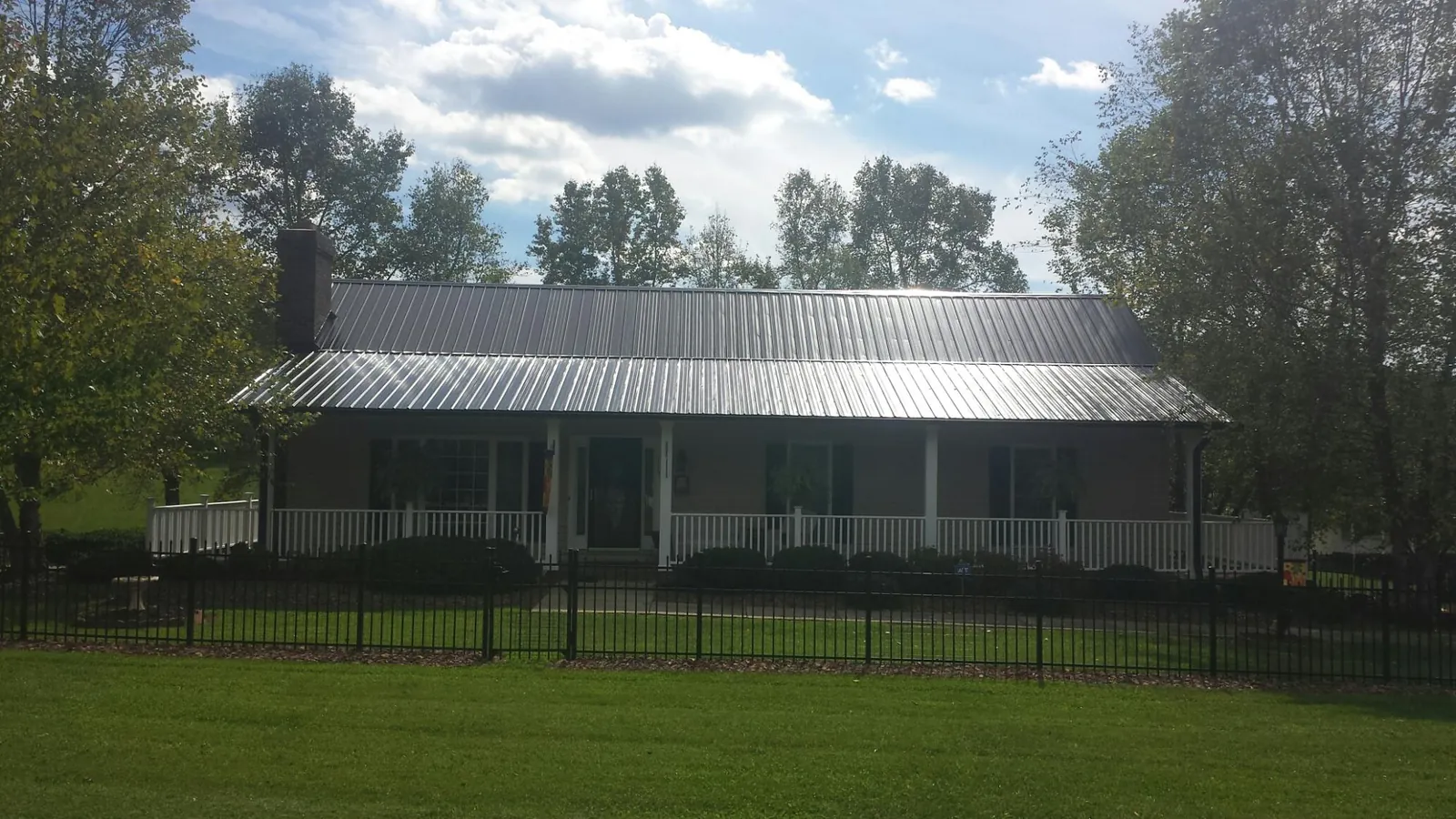 Gray metal roof on a brick ranch with a full width front porch — Gutter Guard Installation work by our crew in Bernhards Bay