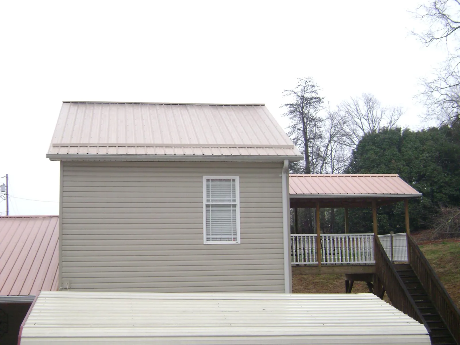 Tan metal roofs on a two story addition and attached porch, from a Roof Replacement job in Bernhards Bay
