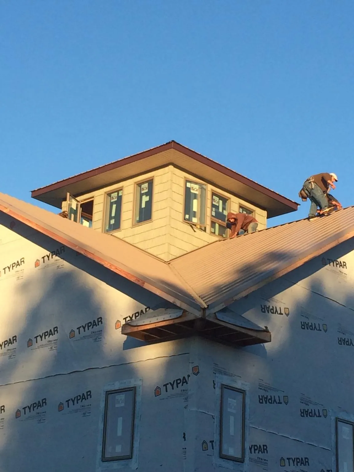 Roofers working around a rooftop cupola on a new metal roof at sunset — Roof Waterproofing in Bernhards Bay by Roofing Brothers